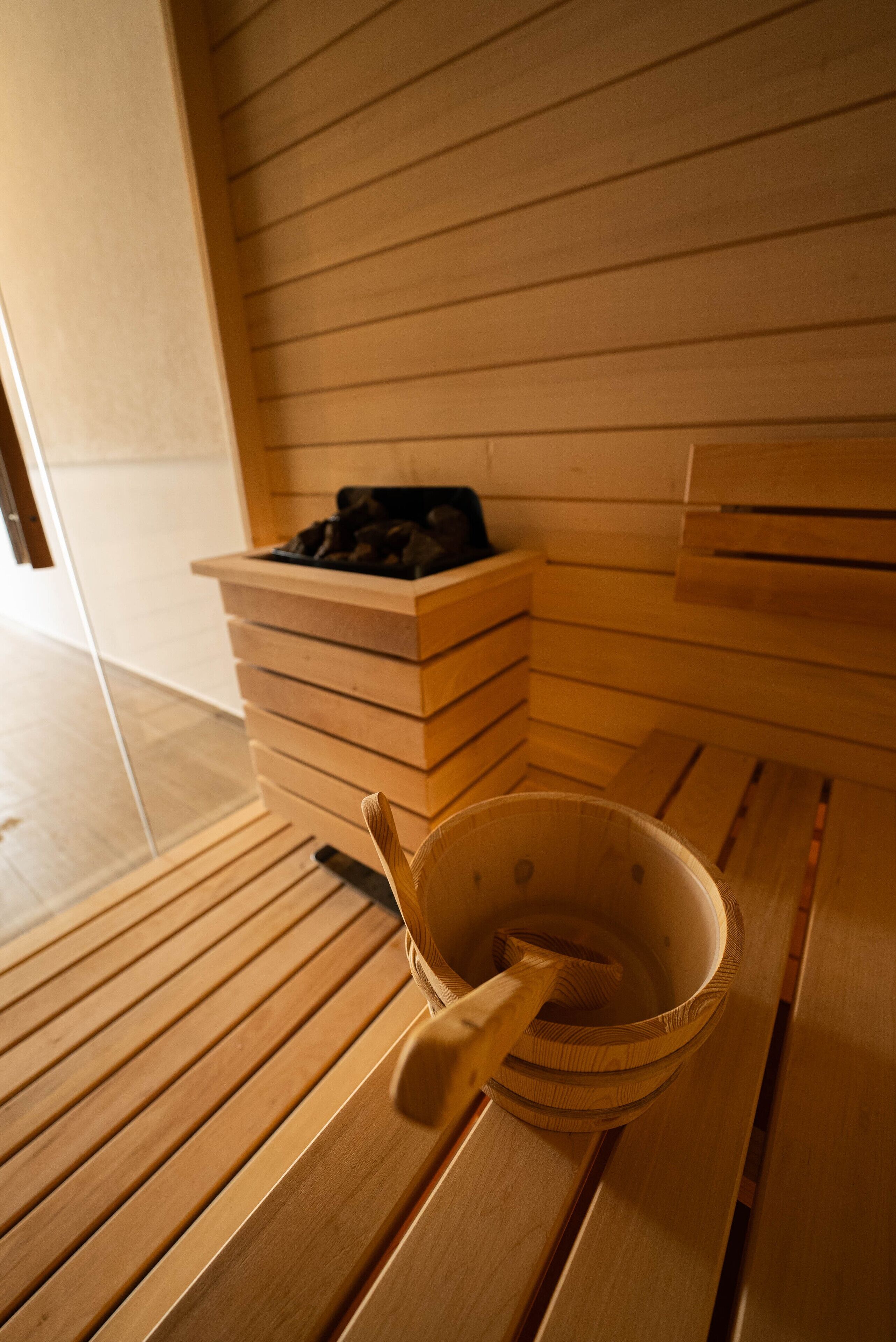 A wooden bench with a bowl and a spoon, a wooden bench with a black object on it, and a wooden wall with horizontal lines.