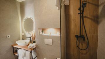 Een moderne badkamer met een houten douche, een ronde spiegel, een witte wastafel en een plank met toiletartikelen.