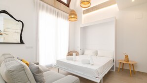 A modern bedroom with a bed, a sofa, a small table, and a hanging light fixture. - Ca Celieta Beach IV. WiFi+Aire Acondicionado (Valencia / València)