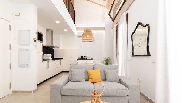 A modern living room with a grey sofa, a round wooden coffee table, and a kitchen in the background. - Ca Celieta Beach IV. WiFi+Aire Acondicionado (Valencia / València)