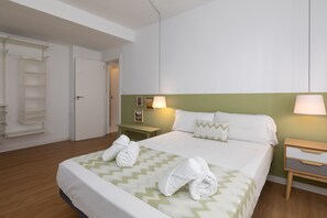 Ein ordentlich eingerichtetes Hotelzimmer mit einem Bett, zwei Nachttischen, einem Schrank und einer Tür.