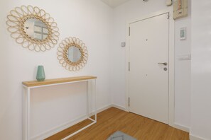 A room with a white door, a white console table with a green vase, and two wall mirrors with a circular design. - Port Area II. WiFi + Air Condition (Valencia)
