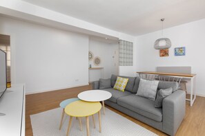 A modern living room with a grey sofa, two round tables, and a wooden dining table. - Port Area II. WiFi + Air Condition (Valencia)