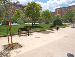 Ein Park mit Bänken, Bäumen und einem Spielplatz.