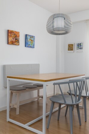 A dining area with a wooden table, grey chairs, a white bench, and a hanging light fixture. - Port Area II. WiFi + Air Condition (Valencia)