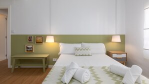 Ein Hotelzimmer mit einem Bett, zwei Nachttischen, einer Ablagefläche, einer grünen Wand und Kunstwerken.