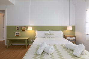 A hotel room with a bed, two bedside tables, a nightstand, a green wall, and artwork. - Port Area II. WiFi + Air Condition (Valencia)