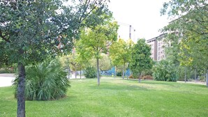 Eine parkähnliche Grünfläche mit Bäumen und einem Gebäude im Hintergrund.