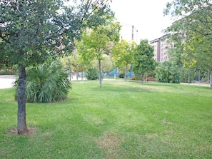 Ein Park mit Gras, Bäumen und einem Gebäude im Hintergrund.