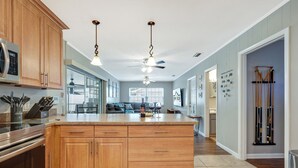 Una cocina moderna con armarios de madera, una isla grande, electrodomésticos de acero inoxidable y un ventilador de techo.
