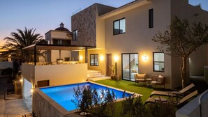 Ein modernes, zweistöckiges Haus mit Swimmingpool, Außenbereich und einer Treppe, die zu der oberen Etage führt.