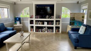 Una sala de estar con una estantería, un televisor y dos sofás azules.