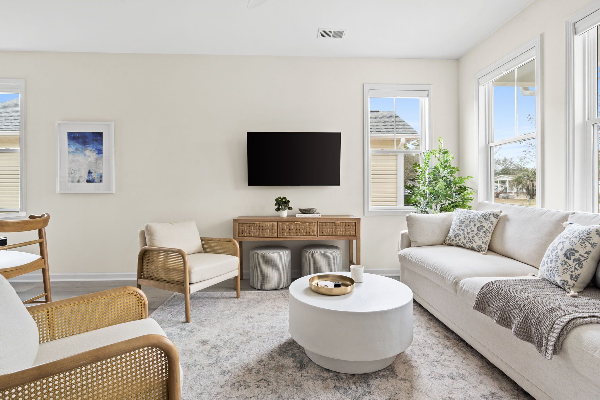 Un salon avec un canapé, des fauteuils, une table basse, un téléviseur et une plante.