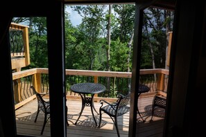 A wooden deck with a round table and two chairs, overlooking a forested area. - Baskerville Private House on 5 Acres inspired by Sherlock Holmes (Augusta)