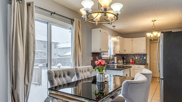 A modern kitchen with white cabinets, a black refrigerator, and a dining area with a glass table and grey chairs. - Indianapolis Home w/ Private Yard ~ 8 Mi to Dtwn! (Indianapolis)