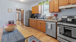 A modern kitchen with wooden cabinets, stainless steel appliances, and a dining area with a wooden table and chairs.