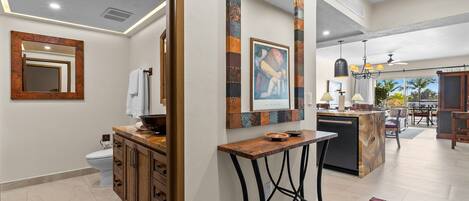 A modern kitchen with a central island, a dining area with a chandelier, and a large mirror with a rustic frame.