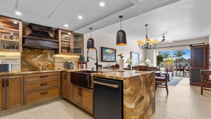 Une cuisine moderne avec des meubles en bois, un îlot en marbre et des luminaires suspendus.