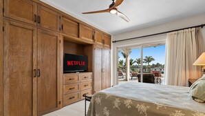 Une chambre à coucher avec un lit, des armoires en bois, une télévision et un balcon avec vue.