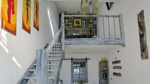 Une pièce de style loft avec un escalier, un coin repas et un lit superposé.