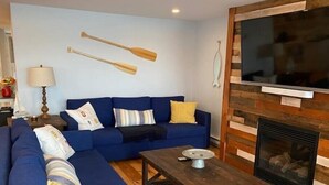 Una sala de estar moderna con un sofá azul, una mesa de centro de madera y una chimenea.