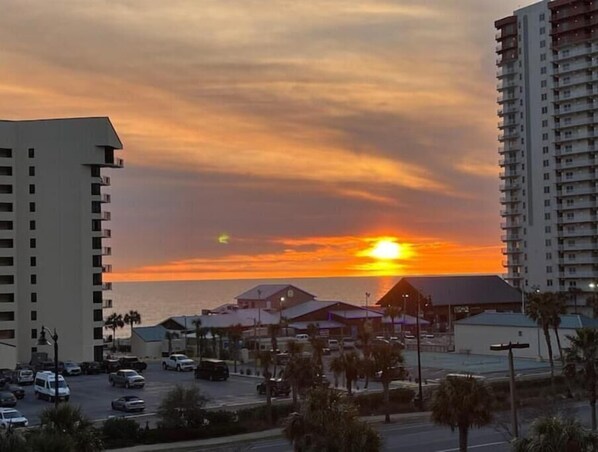 A sunset view with buildings and a parking lot.