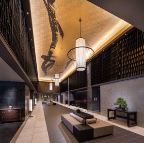 Um hall amplo com teto alto, uma grande área de estar e um lustre moderno.
