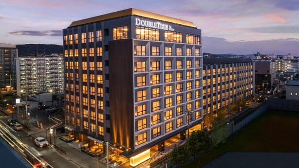 Ein modernes Hotelgebäude mit einem markanten 'DOUBLETREE'-Schild, mehreren Etagen und einer gut beleuchteten Fassade.