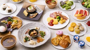 Verschiedene Frühstücksgerichte auf Tellern, darunter Eier, Fleisch und Obst.