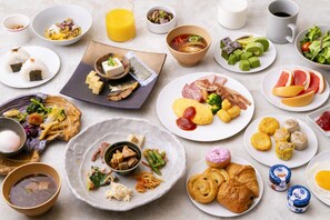 Diverse ontbijtgerechten op borden, zoals eieren, vleeswaren en fruit.