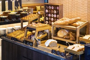 Een bakkerijvitrine met diverse gebakken producten, waaronder brood, gebak en donuts.