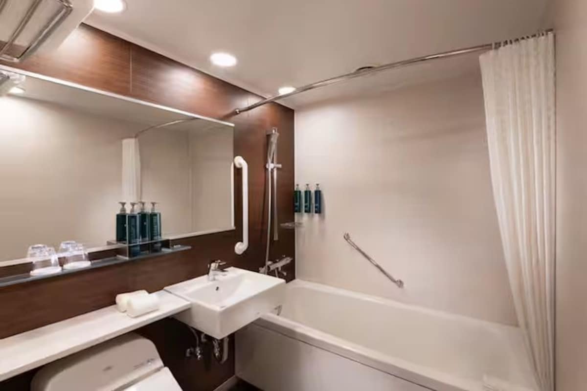 A modern bathroom with a bathtub, a sink, and a mirror.
