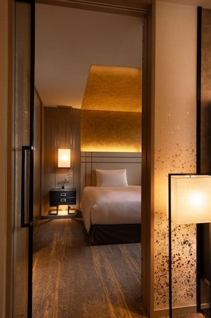 Une chambre d’hôtel comprenant un lit, une table de chevet, une lampe et un mur orné d’un motif texturé.