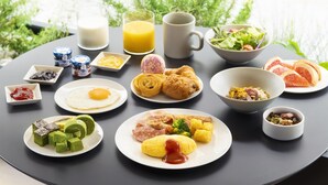 Ein Frühstückstisch mit verschiedenen Speisen, darunter Eier, Gebäck und ein Glas Orangensaft.