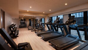 Ein Fitnessstudio mit Laufbändern, Langhantelbänken und einer Hantelbank.