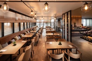 Un restaurant doté de longues tables communes, de petits espaces individuels et de luminaires suspendus.