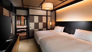 Ein Hotelzimmer mit Bett, Fernseher, Schreibtisch und einem durch eine offene Tür einsehbarer Badezimmer.