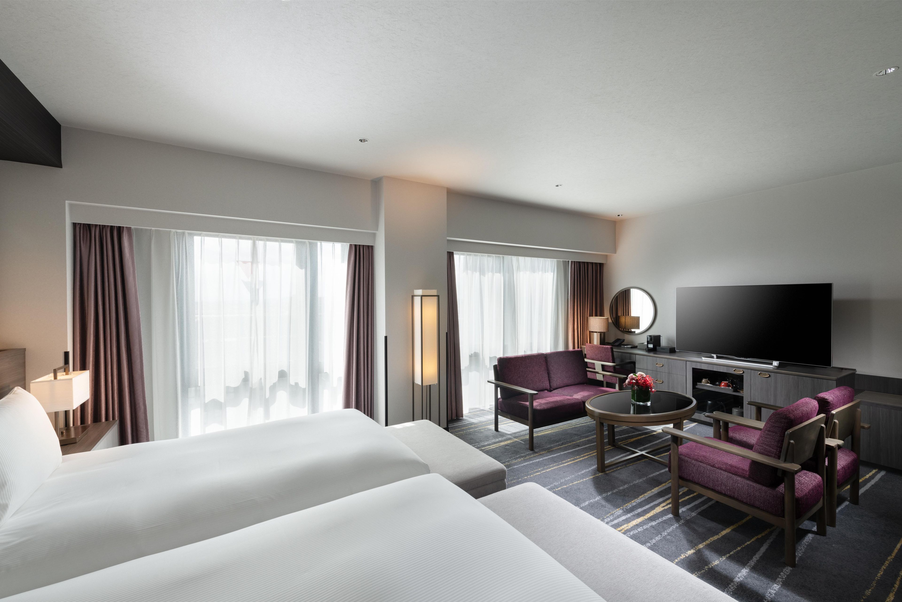 Een hotelkamer met twee bedden, een televisie, een bank en een salontafel.