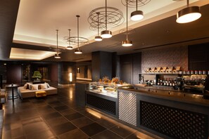 A modern hotel lobby with a seating area, a bar with a wine cooler, and pendant lighting. - Doubletree by Hilton Kyoto Station (Kyoto)
