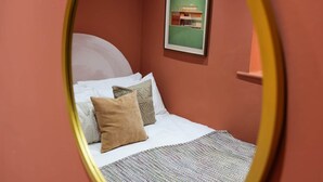 Une pièce avec un lit, des oreillers et un tableau encadré au mur.