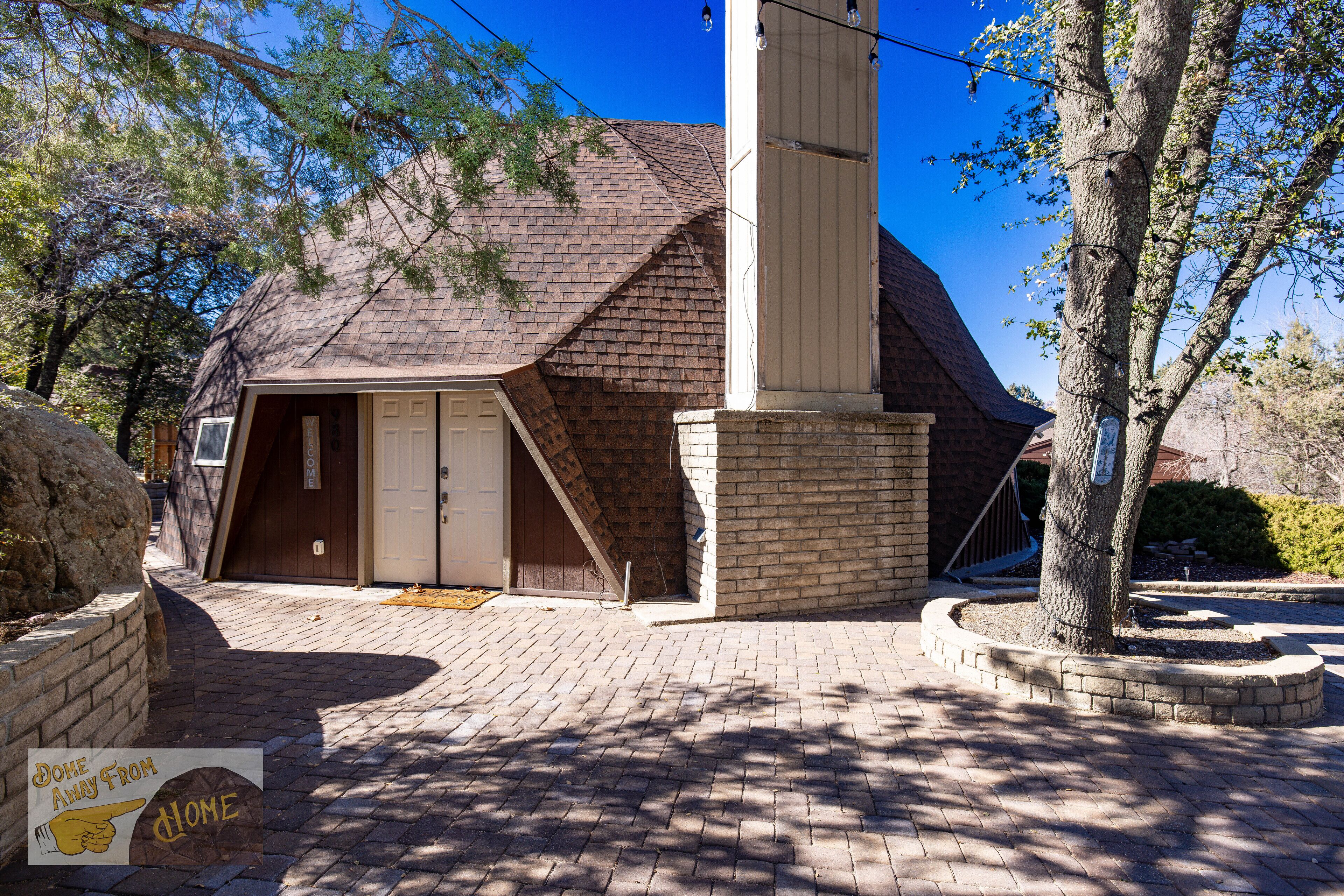 A house with a garage, a brick exterior, and a tree in the front yard.