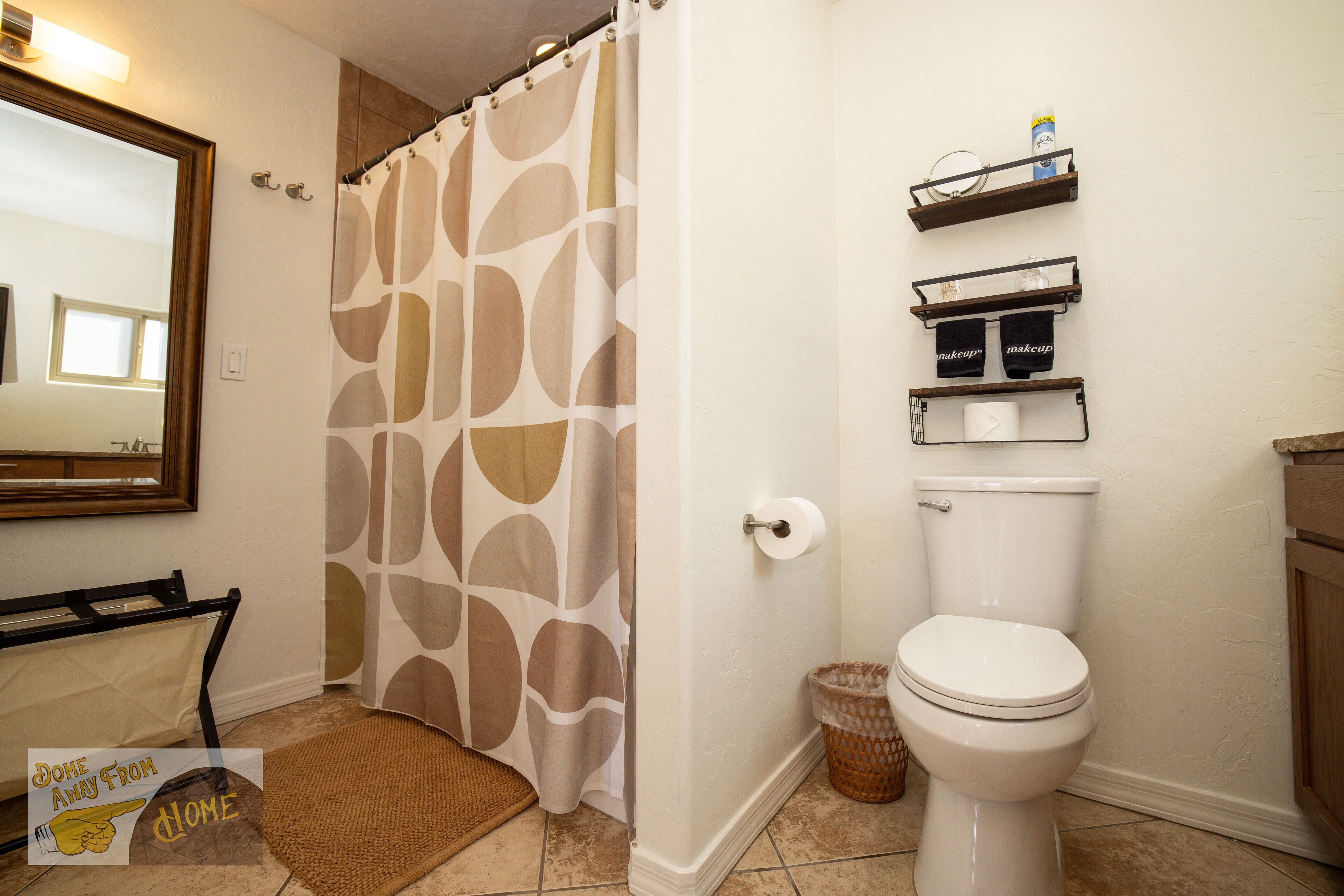 A bathroom with a shower curtain, toilet, and shelves with toiletries.