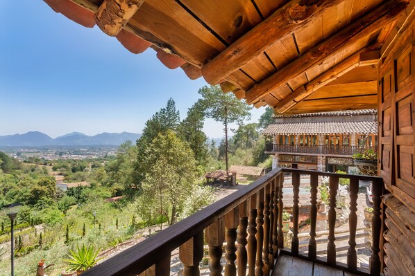 A wooden balcony with a view of a mountainous landscape.