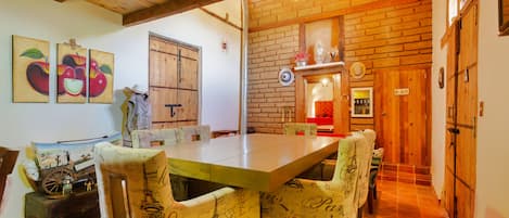 Un comedor con una mesa larga, sillas de madera y una pared de ladrillo.
