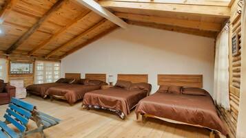 A log cabin-style room with three wooden beds, a blue bench, and a wooden ceiling.
