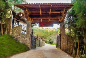 Un sendero conduce a un edificio de fachada de piedra y una pérgola de madera.