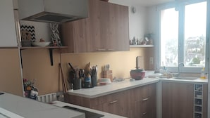Et moderne køkken med træskabe, en hvid bordplade og et stort vindue, der lukker naturligt lys ind.