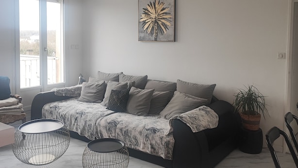 En moderne stue med sofa, to gulvlamper, en potteplante og et stort vindue.