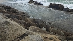 En stenet kystlinje med bølger der slår mod klipperne.