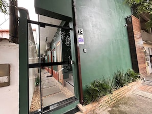 Une entrée d’immeuble agrémentée d’un mur végétal, d’une porte numérotée et d’un petit espace jardin.